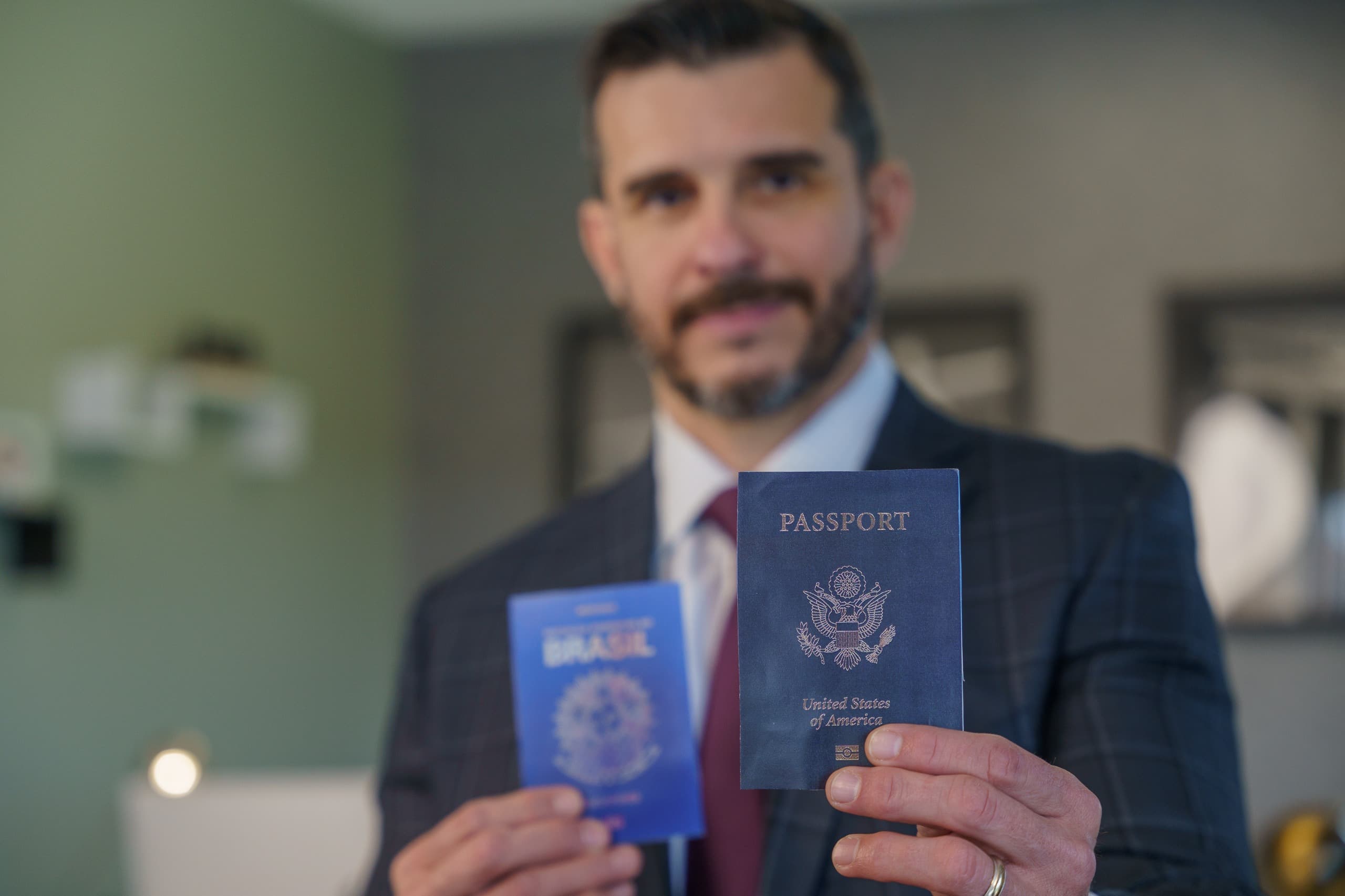 André Linhares segurando um passaporte brasileiro e um passaporte americano